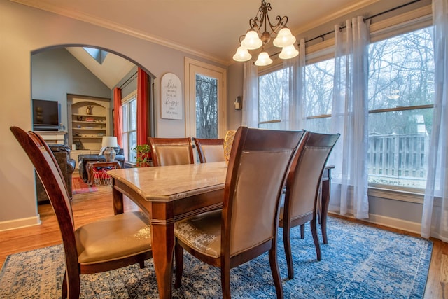 dining space with arched walkways, wood finished floors, and crown molding