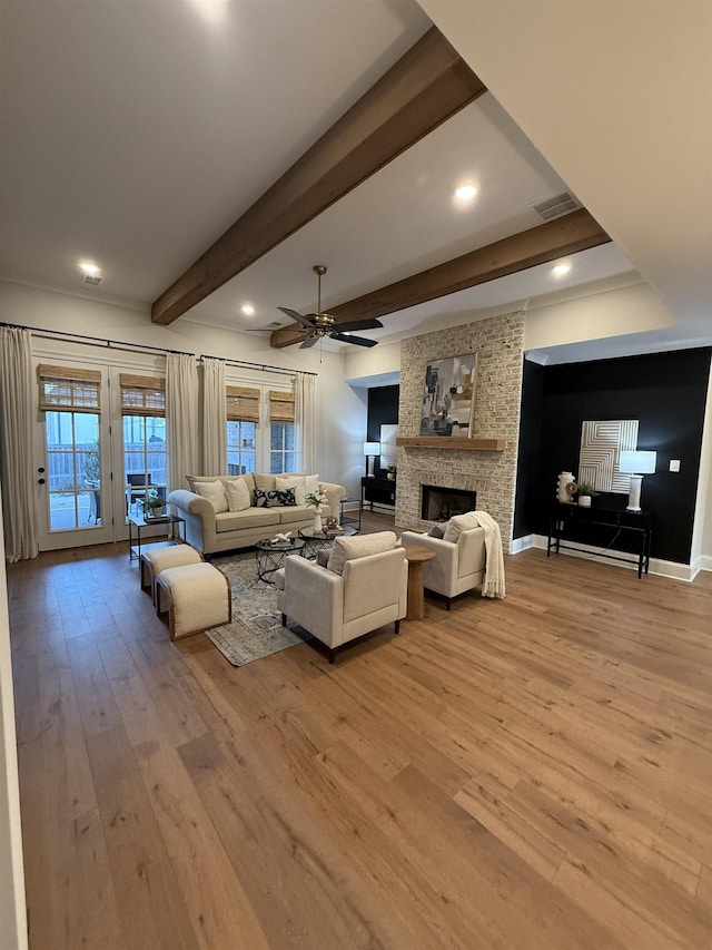 living room with light wood finished floors, a fireplace, visible vents, and beam ceiling