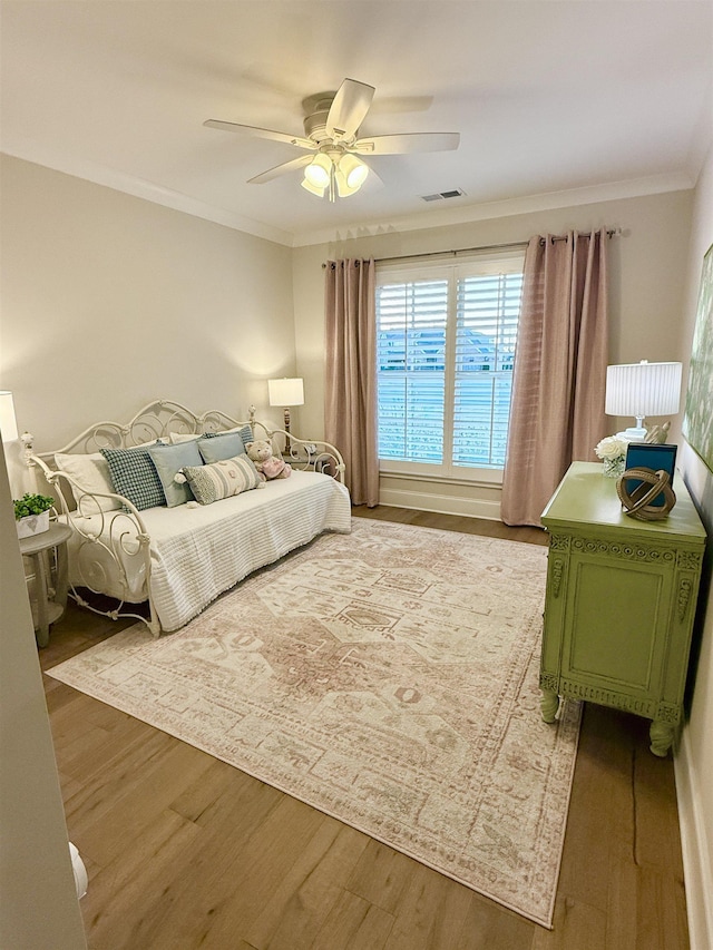 bedroom featuring crown molding, visible vents, ceiling fan, and wood finished floors