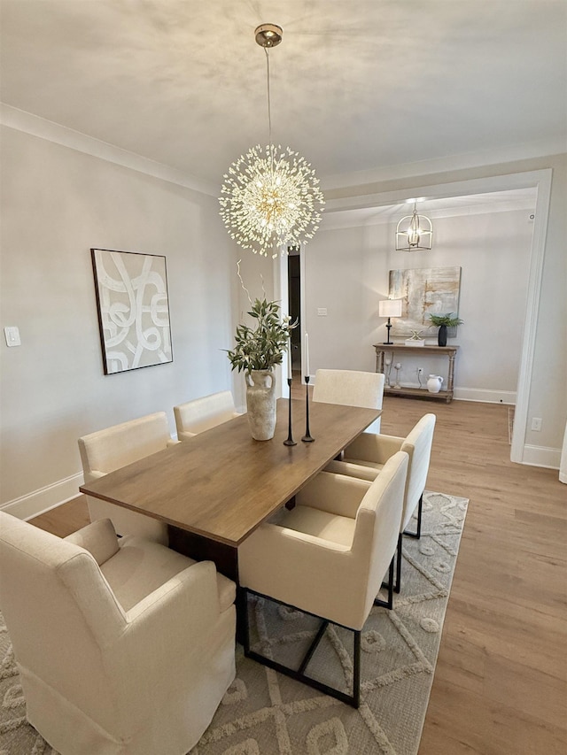 dining space with ornamental molding, wood finished floors, baseboards, and an inviting chandelier