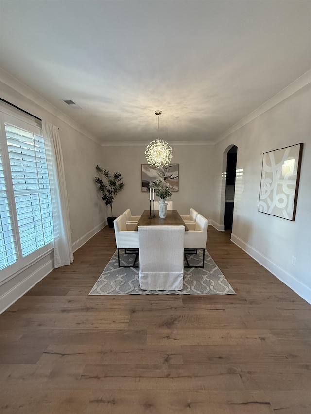 unfurnished dining area with arched walkways, wood finished floors, visible vents, and crown molding