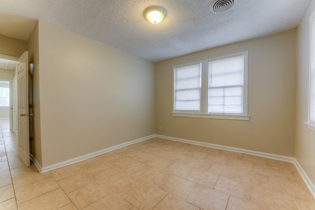 spare room with visible vents, a textured ceiling, baseboards, and light tile patterned floors