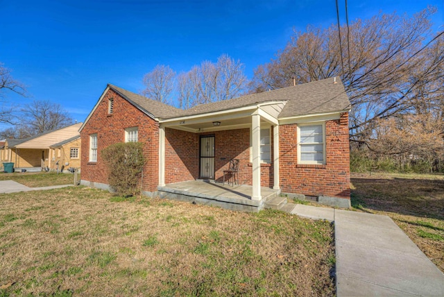 view of front of house featuring a porch, brick siding, a shingled roof, and a front lawn