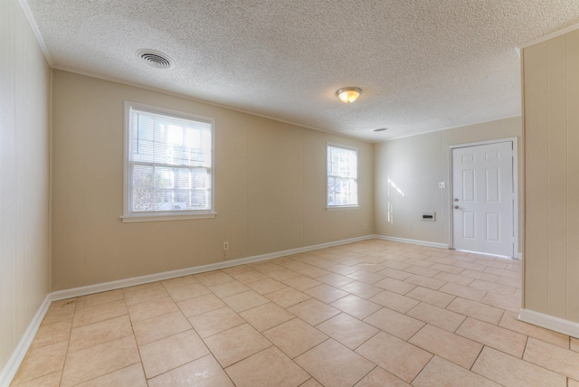 unfurnished room featuring light tile patterned floors, baseboards, visible vents, and crown molding