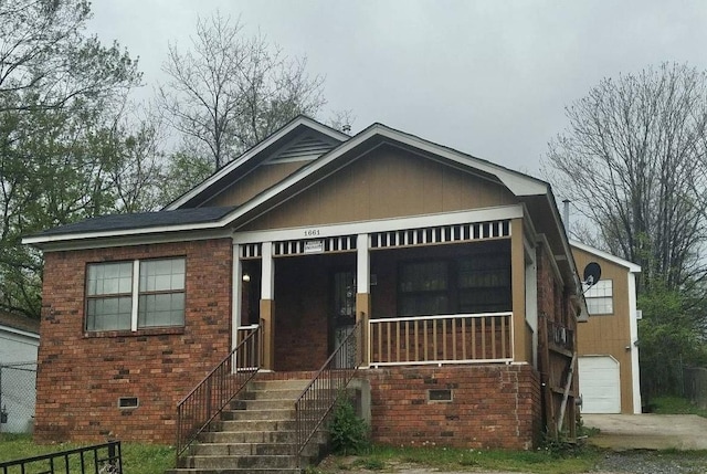 view of front facade featuring a porch, a garage, brick siding, crawl space, and stairway