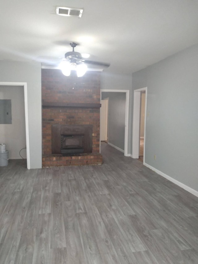 unfurnished living room featuring electric panel, a fireplace, visible vents, and wood finished floors