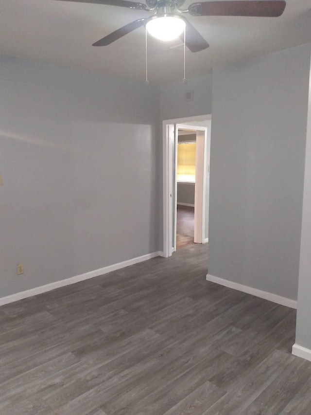 spare room with dark wood-style floors, a ceiling fan, and baseboards