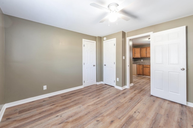 spare room with light wood-type flooring, ceiling fan, and baseboards