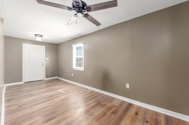 spare room featuring light wood-style floors, baseboards, and a ceiling fan