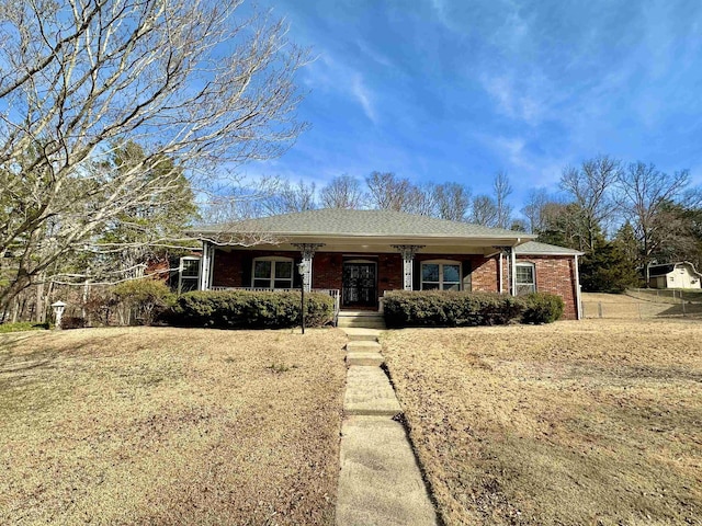 ranch-style house with covered porch, brick siding, and roof with shingles