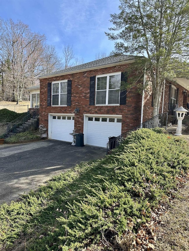 view of front facade with a garage, aphalt driveway, and brick siding