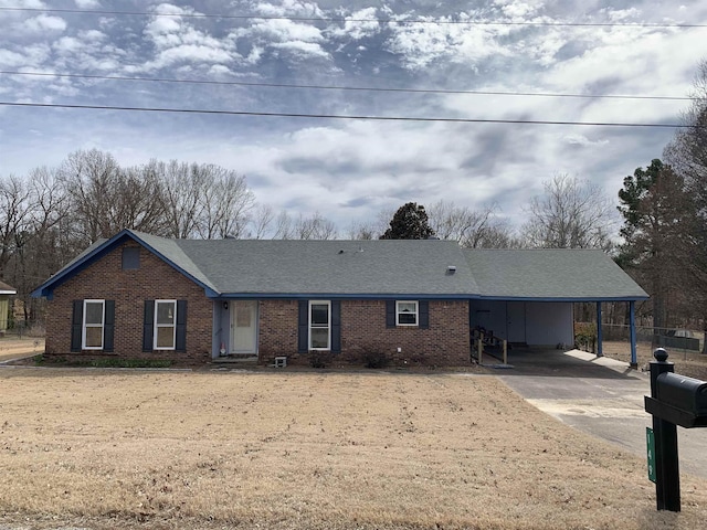 ranch-style home featuring brick siding, a shingled roof, a carport, and concrete driveway