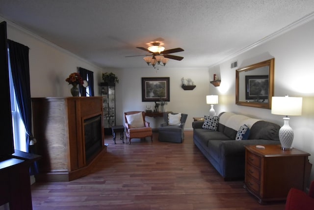 living room with visible vents, wood finished floors, a textured ceiling, crown molding, and a fireplace