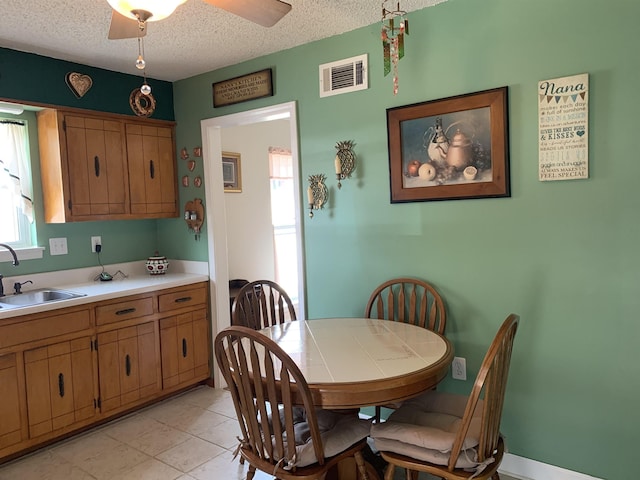 dining area featuring a wealth of natural light, a ceiling fan, visible vents, and a textured ceiling