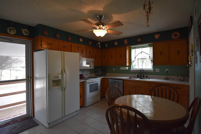 kitchen featuring tile counters, a sink, a textured ceiling, ceiling fan, and white appliances