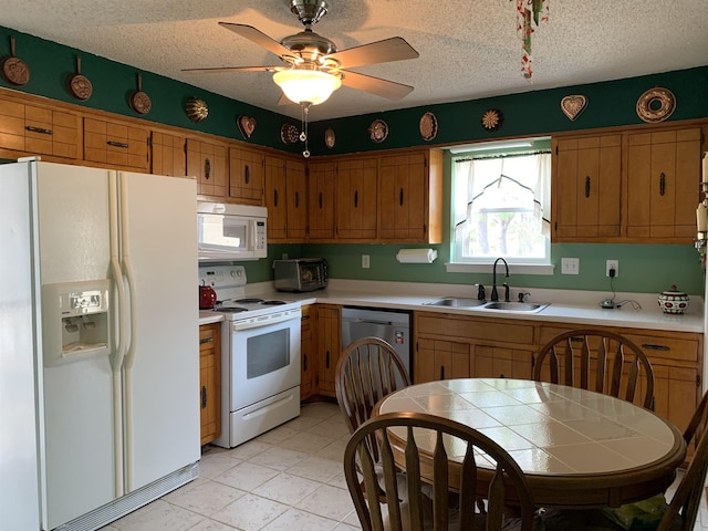 kitchen featuring white appliances, a textured ceiling, light countertops, and a sink