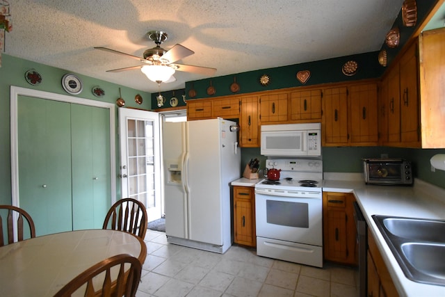 kitchen featuring brown cabinetry, white appliances, light countertops, and a sink