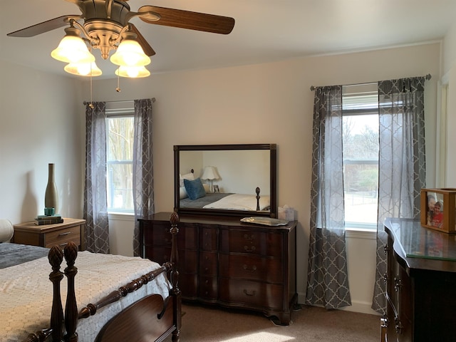 carpeted bedroom featuring a ceiling fan, multiple windows, and baseboards