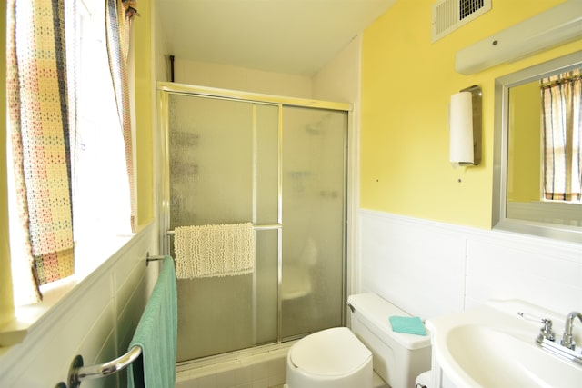 full bathroom featuring a wainscoted wall, plenty of natural light, a sink, and visible vents