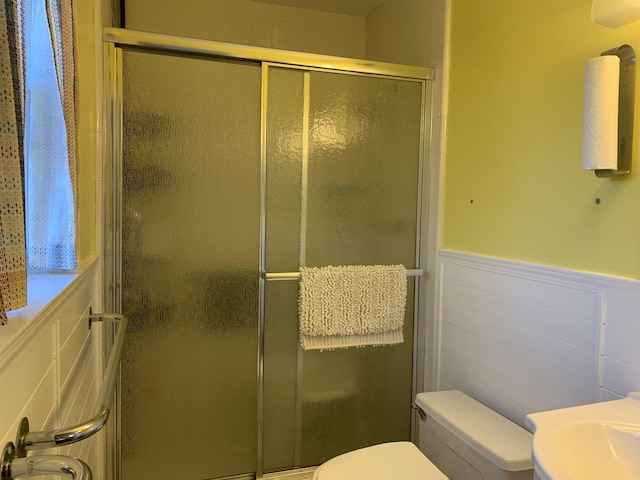 full bath with a wainscoted wall, a stall shower, vanity, and toilet