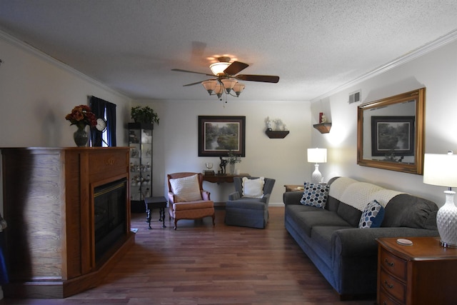 living area with visible vents, a glass covered fireplace, ornamental molding, wood finished floors, and a textured ceiling