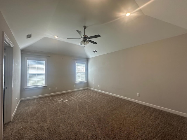 empty room featuring carpet, visible vents, vaulted ceiling, and baseboards