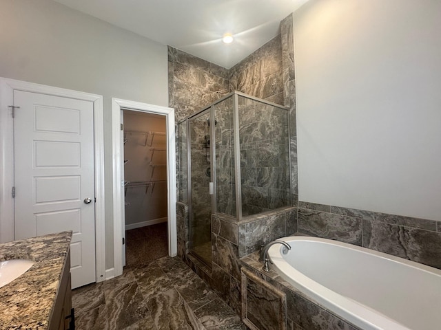 bathroom with a stall shower, a spacious closet, a bath, and vanity