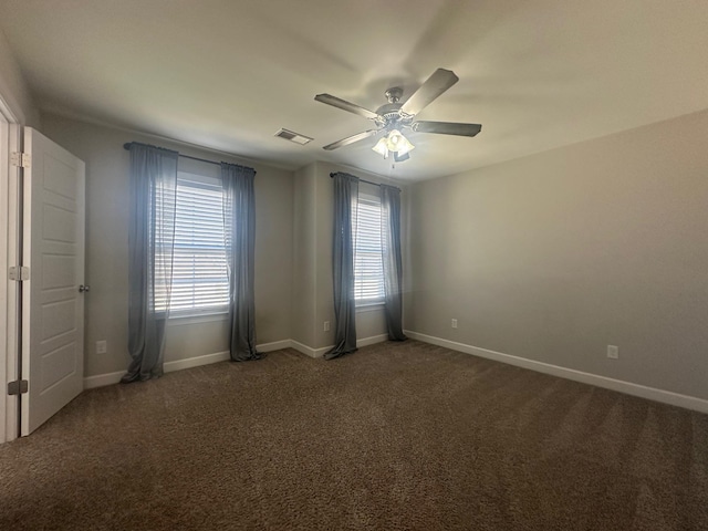 carpeted empty room featuring a wealth of natural light, visible vents, ceiling fan, and baseboards