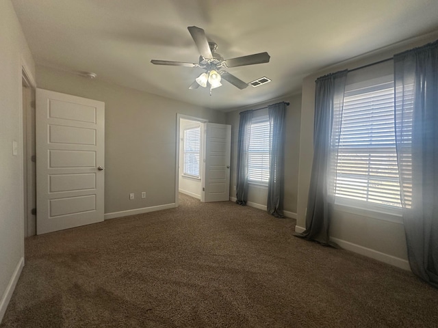 unfurnished room with carpet floors, visible vents, and baseboards