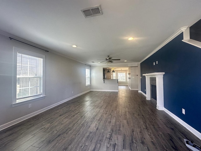 unfurnished living room with ornamental molding, visible vents, a fireplace, and dark wood-type flooring