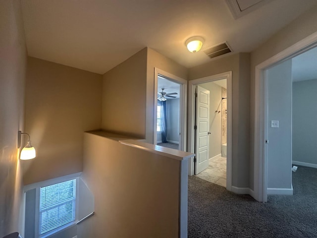 corridor featuring visible vents, carpet, an upstairs landing, and baseboards