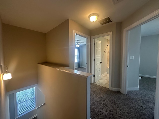 corridor featuring carpet floors, visible vents, an upstairs landing, and baseboards