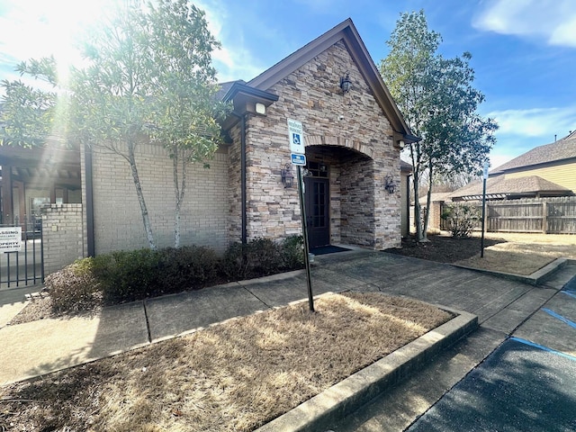 view of front facade with stone siding, fence, and brick siding