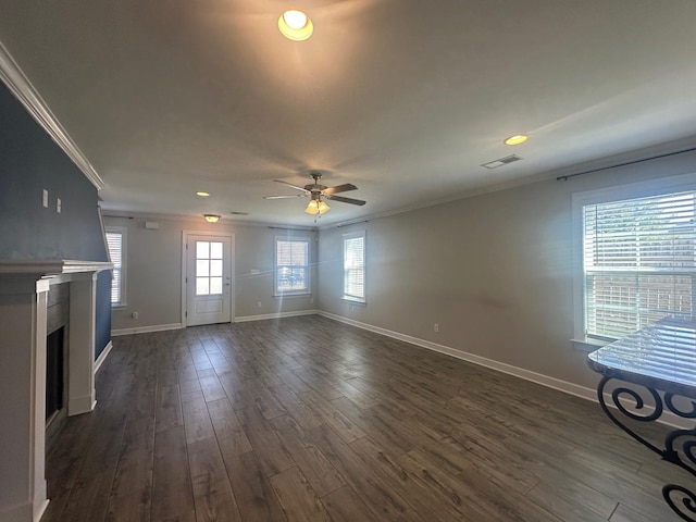 unfurnished living room with dark wood-type flooring, a fireplace, visible vents, baseboards, and crown molding