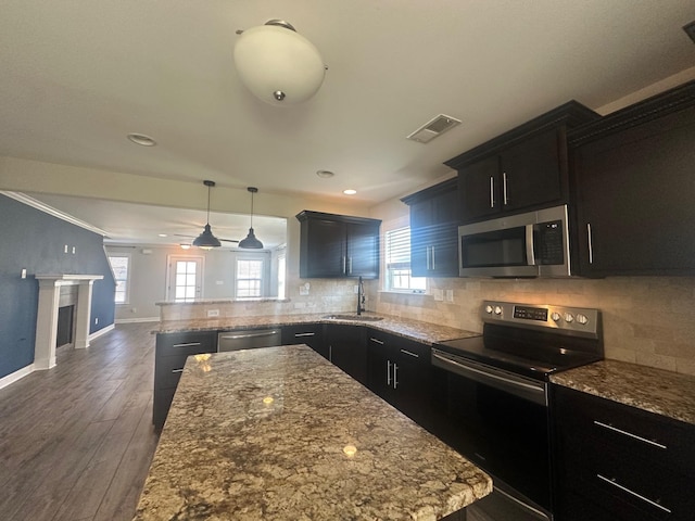 kitchen with stainless steel appliances, visible vents, backsplash, dark wood-type flooring, and a sink