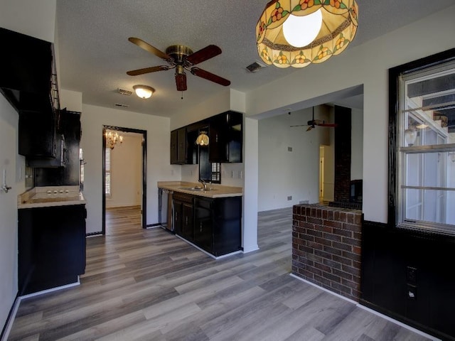 kitchen featuring visible vents, light countertops, dark cabinetry, a textured ceiling, and a sink