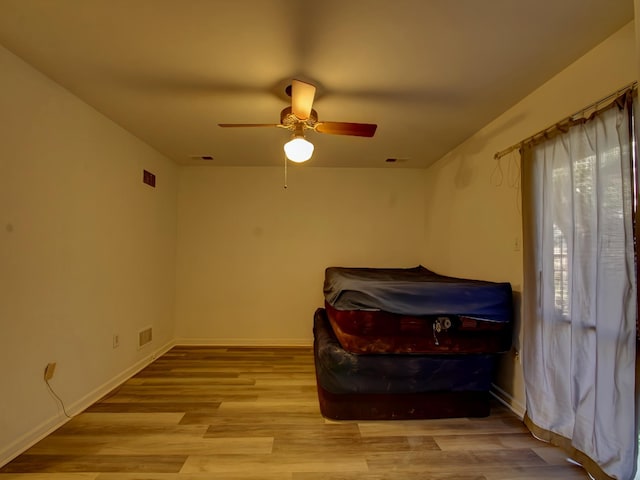 bedroom with a ceiling fan, visible vents, baseboards, and wood finished floors