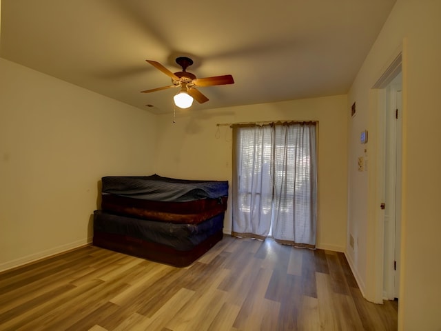 bedroom featuring a ceiling fan, baseboards, and wood finished floors