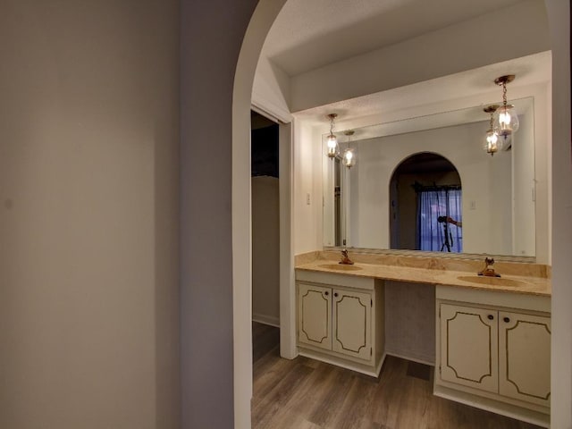 bathroom with double vanity, a sink, and wood finished floors