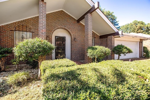 entrance to property with a garage and brick siding