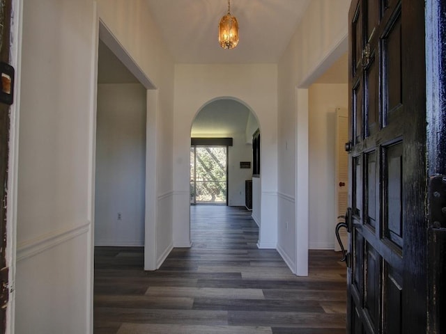 entrance foyer featuring arched walkways, dark wood finished floors, and baseboards