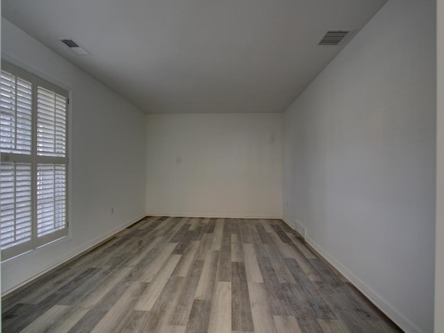 spare room with visible vents, baseboards, and wood finished floors