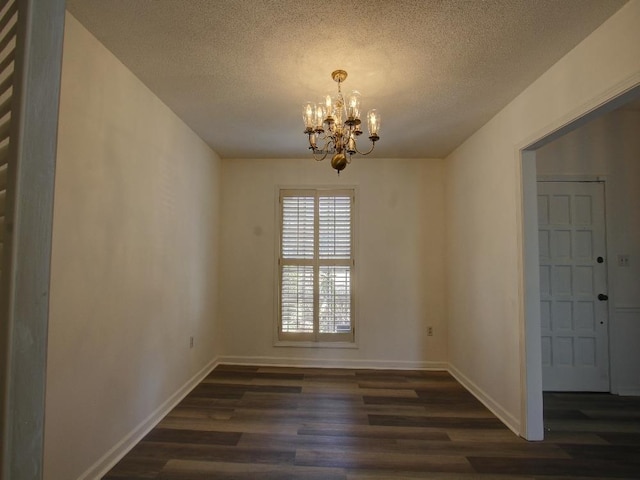 unfurnished dining area featuring baseboards, a textured ceiling, a chandelier, and wood finished floors