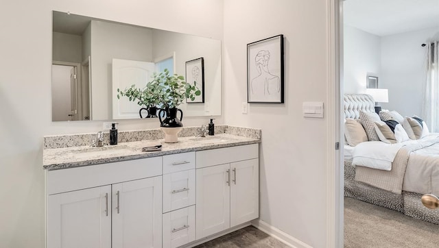 bathroom with double vanity, baseboards, a sink, and ensuite bathroom