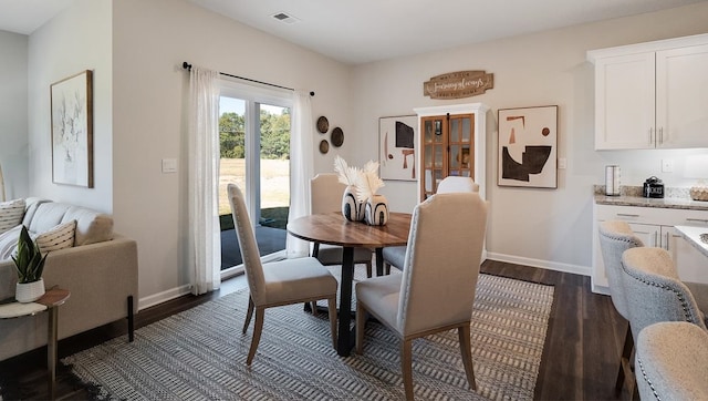 dining space featuring dark wood finished floors, visible vents, and baseboards