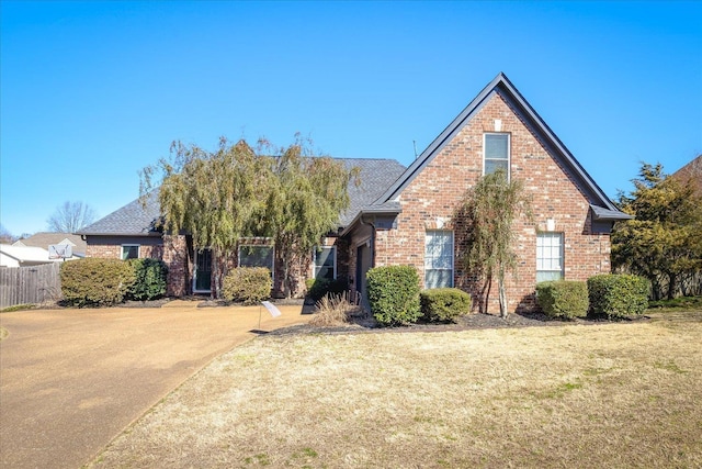 view of front facade featuring a front yard, brick siding, and fence