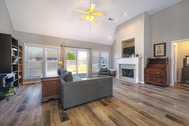 living room featuring a fireplace, visible vents, ceiling fan, wood finished floors, and high vaulted ceiling