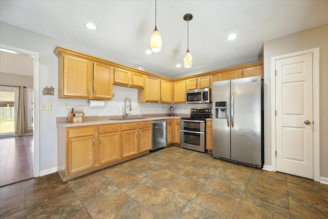 kitchen featuring baseboards, appliances with stainless steel finishes, light countertops, pendant lighting, and a sink