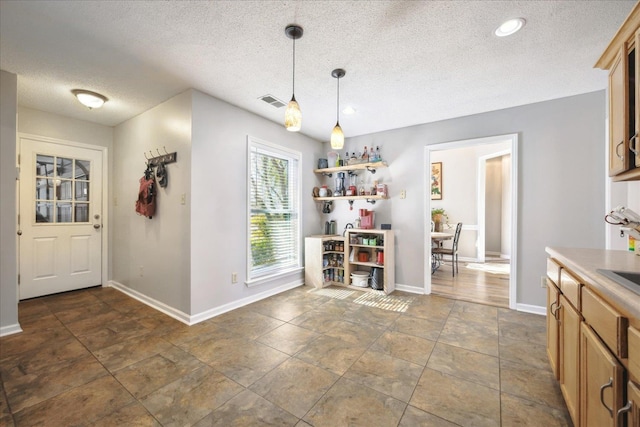 interior space with a textured ceiling, visible vents, and baseboards