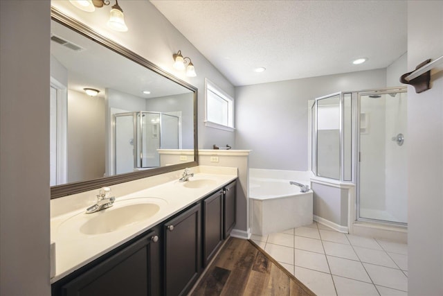 bathroom with a shower stall, a textured ceiling, visible vents, and a sink